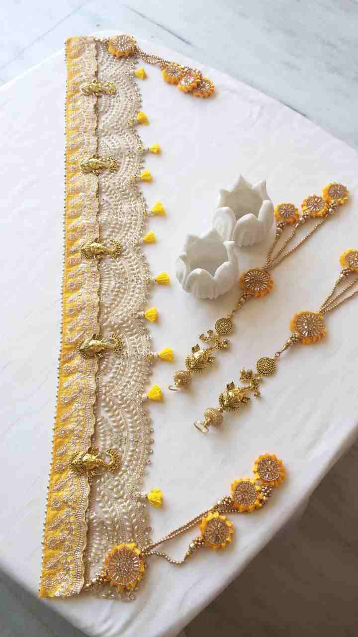 A yellow Bandarwal adorned with metal Ganesha and pearl work