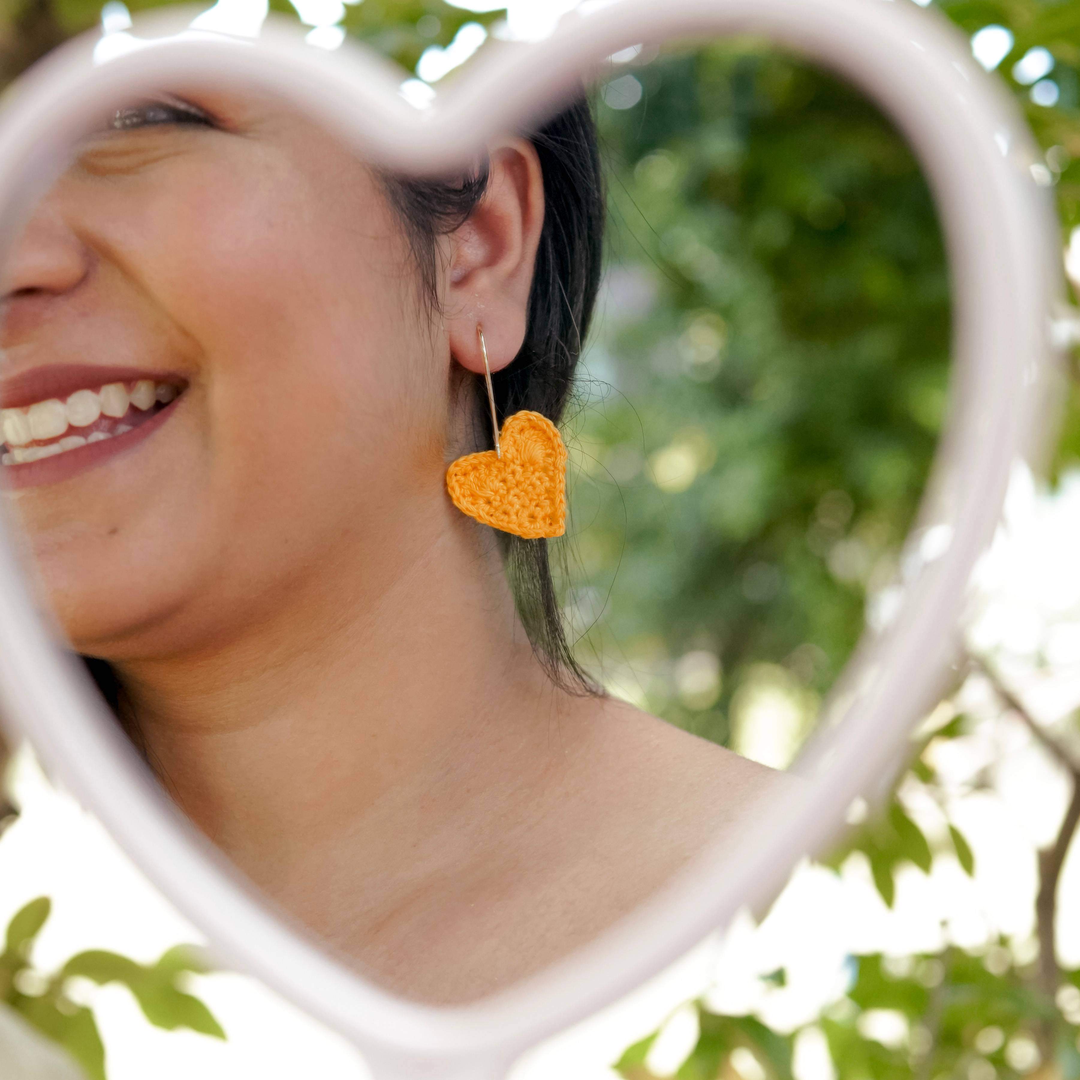 Yellow crochet heart earrings modeled, adding a touch of sunshine to the outfit