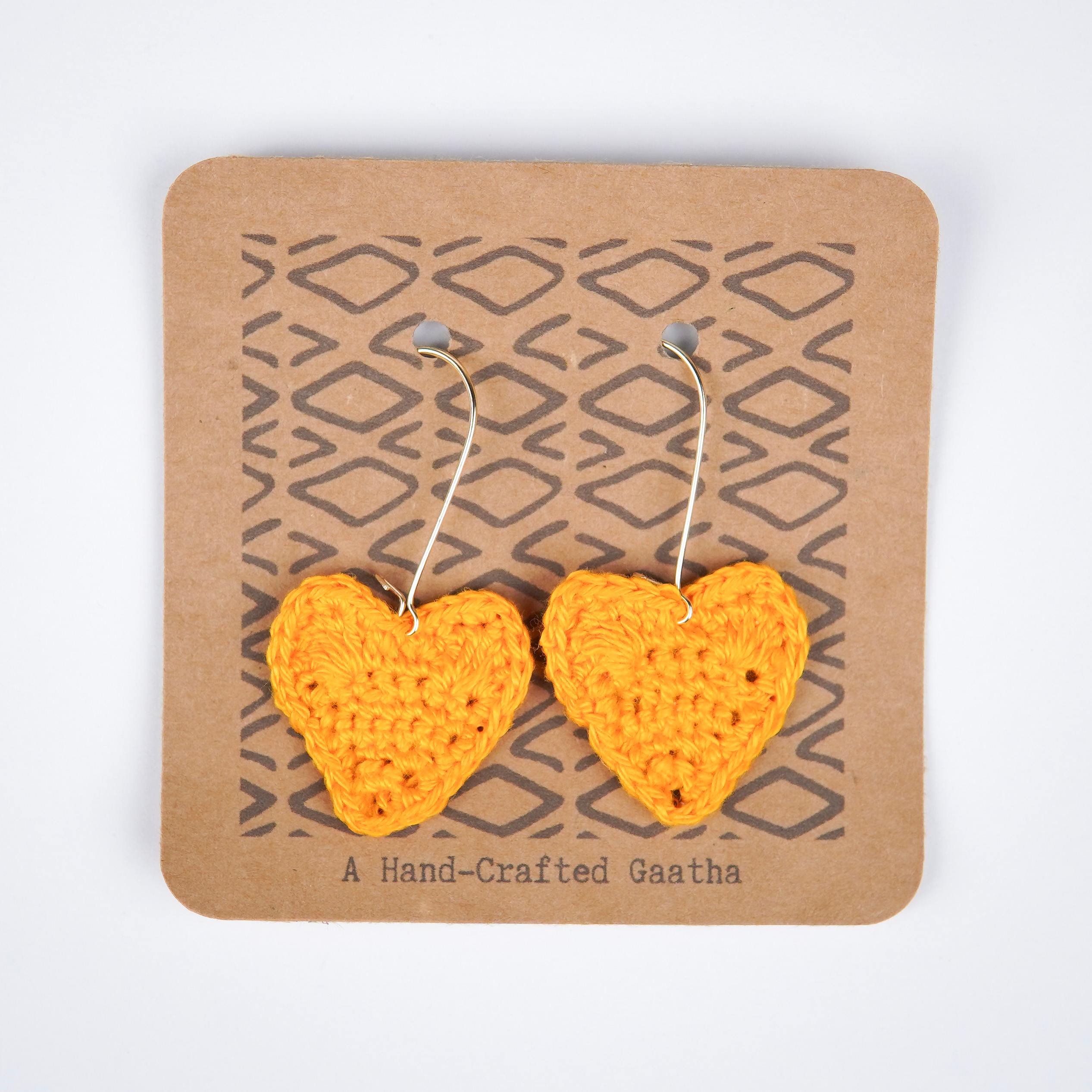 Close-up of sunshine yellow crochet heart earrings, showcasing the intricate details
