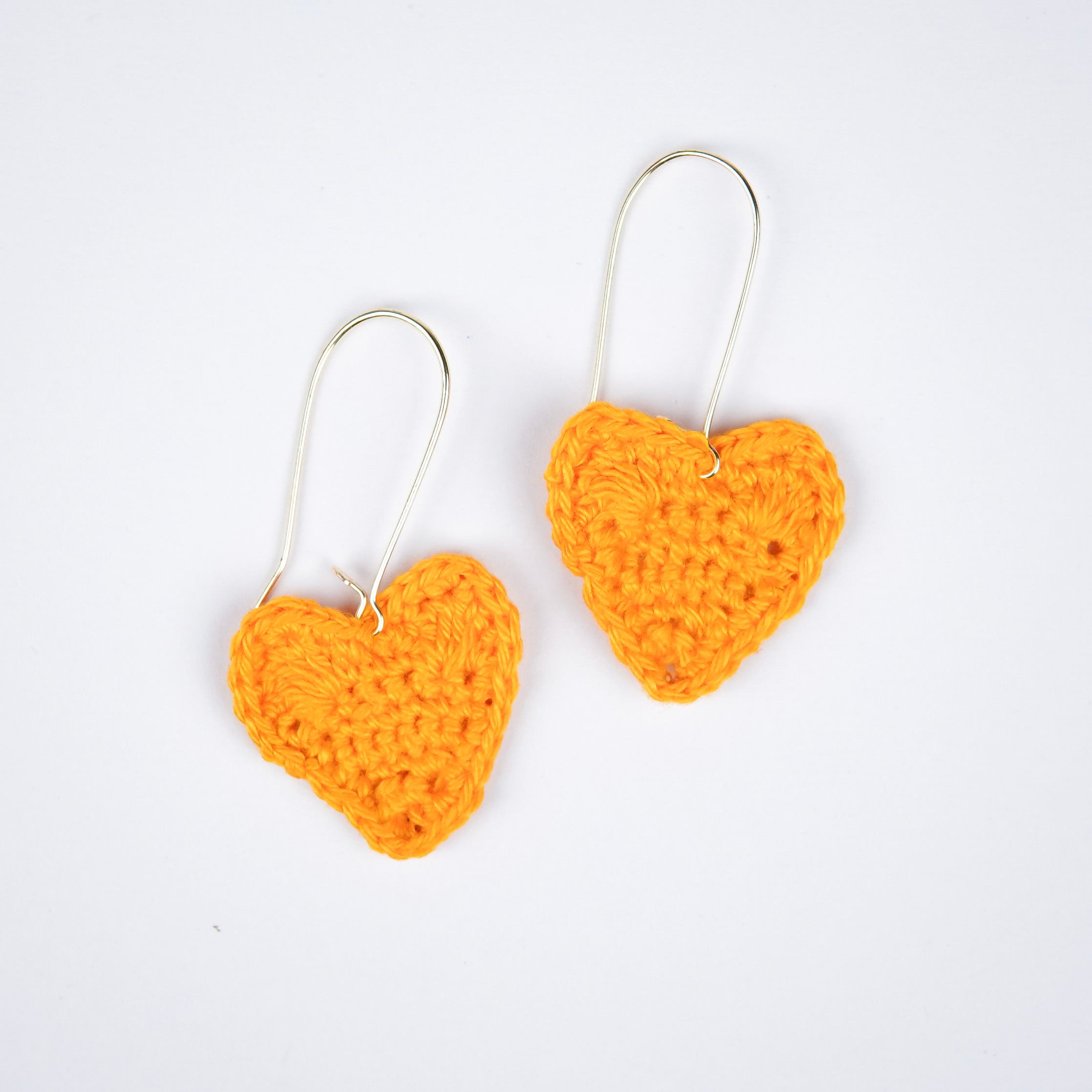 Close-up of sunshine yellow crochet heart earrings, showcasing the intricate details