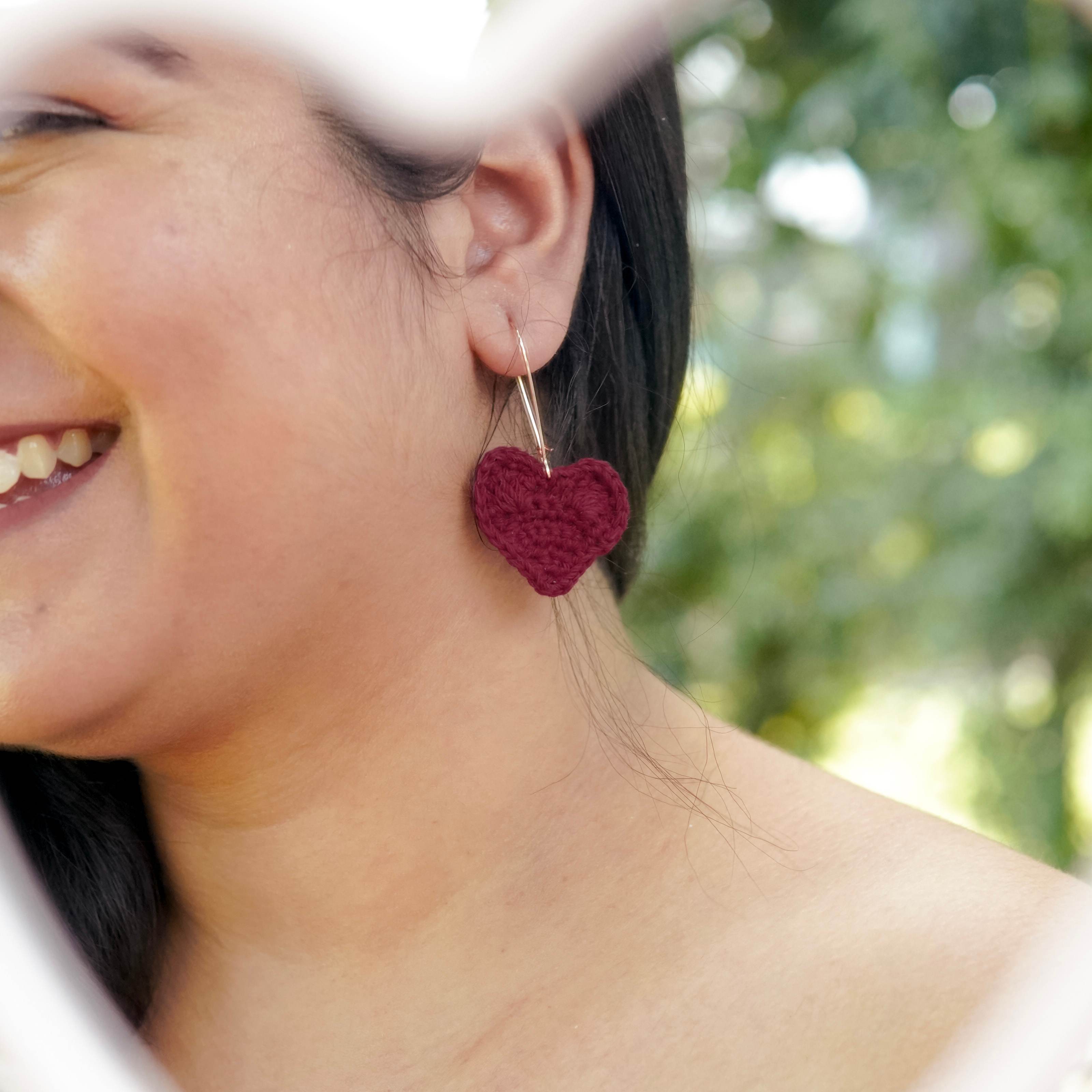 Model wearing maroon crochet heart earrings, showcasing a touch of sophistication.